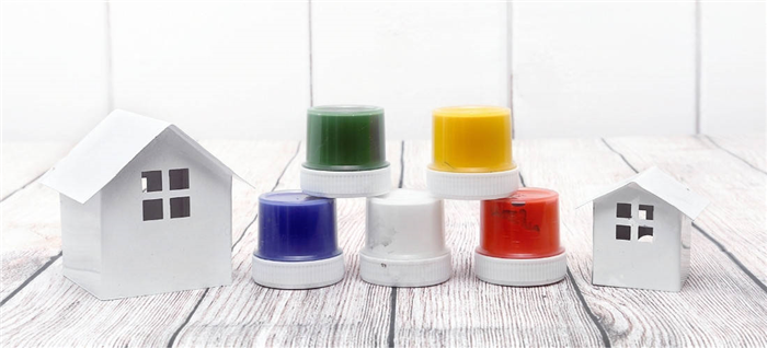 Пять баночек с разноцветной краской стоят между двумя белыми миниатюрными домиками.