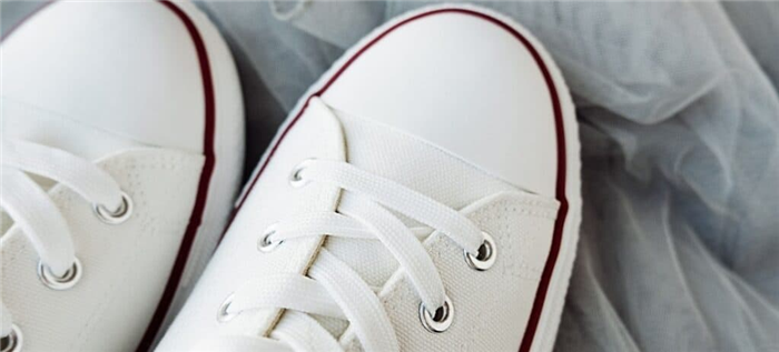 Новая пара белых кроссовок с темно-красной полосой чуть выше подошвы.