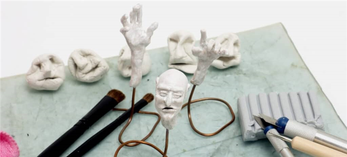 Головы и руки созданы из полимерной глины в окружении различных скульптурных инструментов.