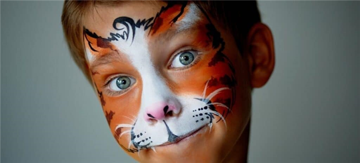 Молодой парень с лицом, разрисованным под тигра.