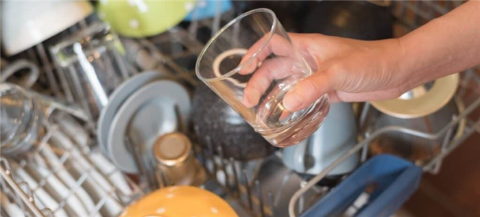 Чистый стакан вынимается из посудомоечной машины.