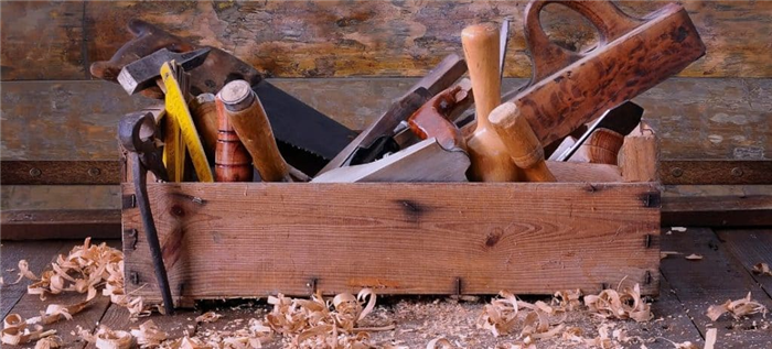 Старый деревянный ящик для инструментов, наполненный ручными инструментами.