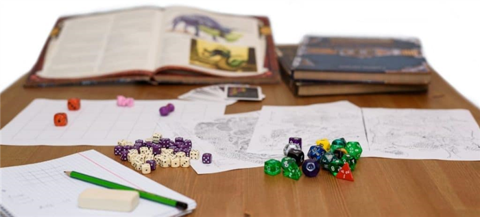 Игровые элементы D&D, книги и бумаги, разложенные на столе.