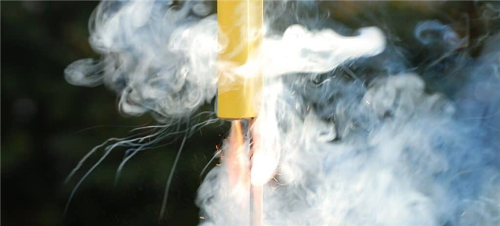 Модель ракеты, окруженная дымом, с огнем, вырывающимся из нижней части перед самым взлетом.