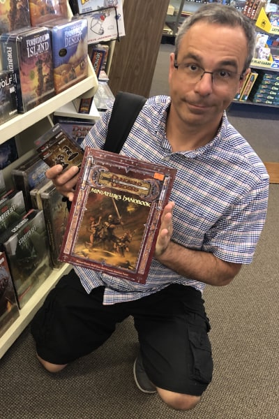 Рич держит в руках справочник по D&D (Dungeons and Dragons) в магазине хобби. Справочники очень полезны, когда вы только начинаете играть.