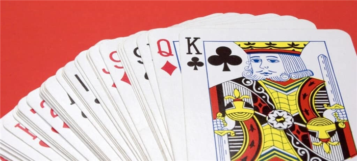 Перевернутые игральные карты, разложенные веером на красном фоне.