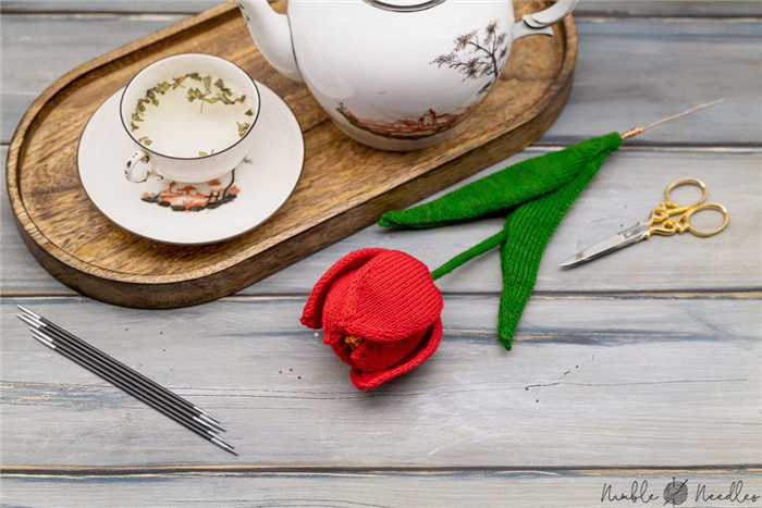 готовый узор для вязания тюльпана на деревянной доске с чайником и чашкой на заднем плане
