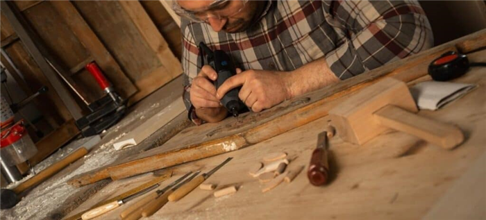 Мужчина использует ротационный инструмент и резцы для гравировки по дереву.
