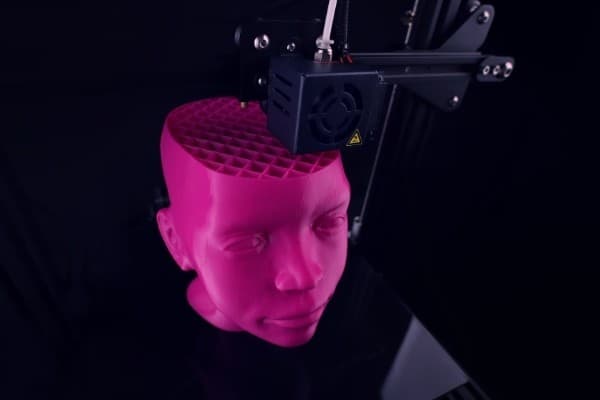 Большая розовая форма головы печатается на 3D-принтере.
