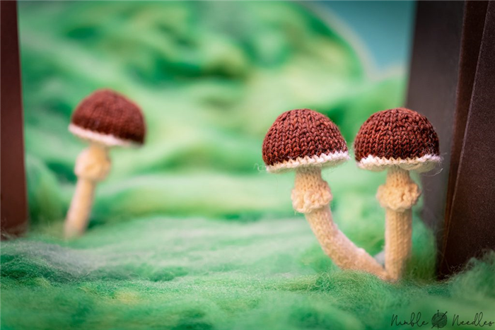три гриба в искусственном лесу возле картонного пня