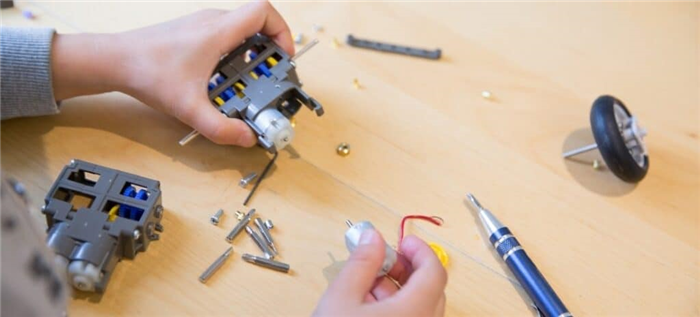 Маленький мальчик собирает вместе компоненты и провода для проекта STEM-модели.