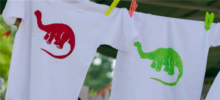 Две свежеокрашенные футболки с изображением красочных динозавров.