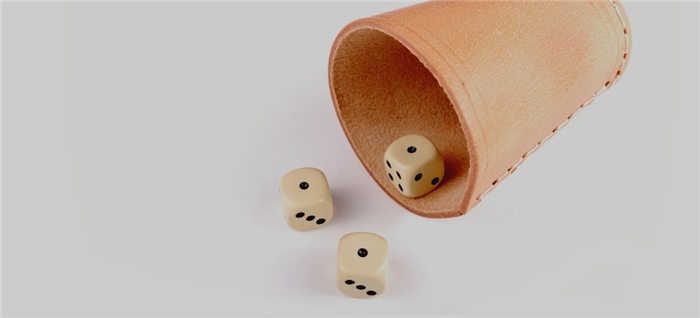 Три игральные кости бросают из кожаной чашки для игры в кости.