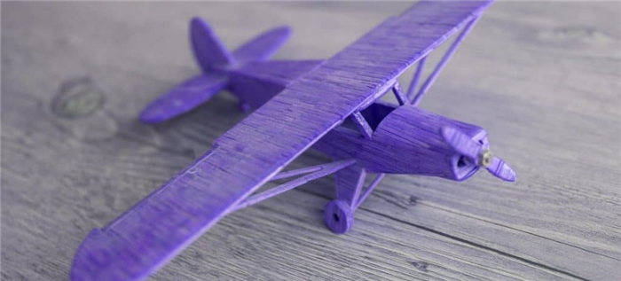 Собранная деревянная модель самолета, окрашенная в фиолетовый цвет.